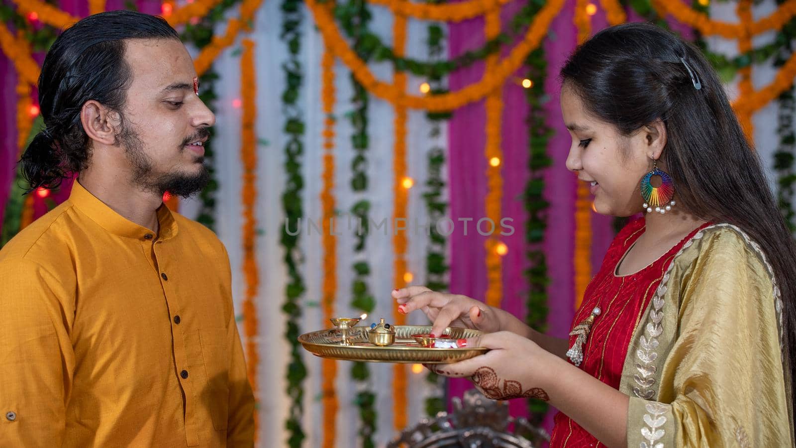 Indian families celebrating Raksha Bandhan festival a festival to celebrate the bond between brother and sister. Rakhi celebration in India. Feeding sweets, applying tikka.