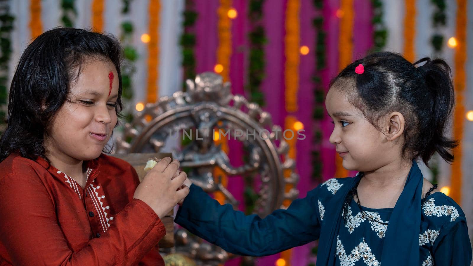 Indian families celebrating Raksha Bandhan festival a festival to celebrate the bond between brother and sister. Rakhi celebration in India. Feeding sweets, applying tikka.