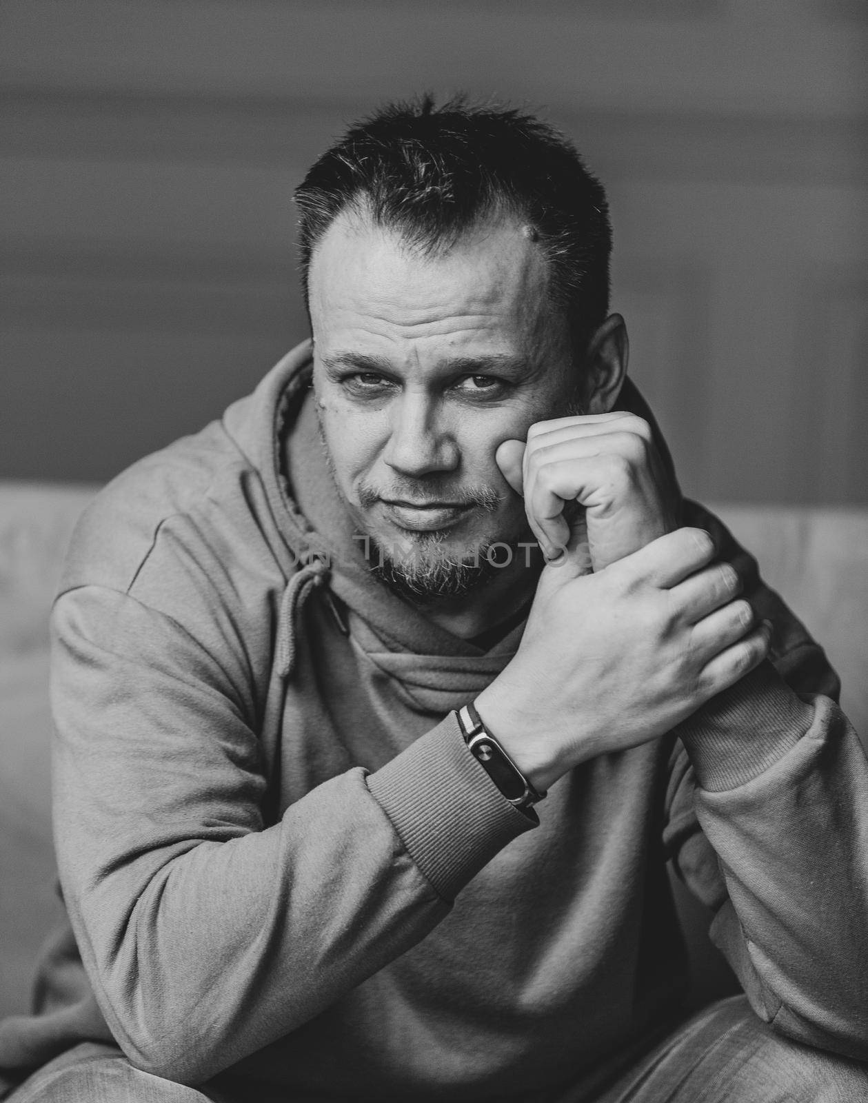 Male Portrait, Smart Man Looks Expressively At Camera, Confident Bearded Caucasian Guy In Casual Wear Touching His Face With Joined Hands, Greyscale Image, Studio Shot