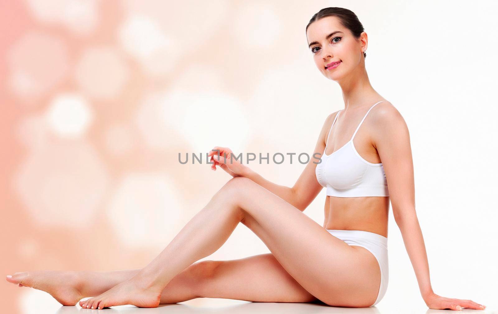 Pretty woman with slim beautiful body sitting against an abstract background with circles and copyspace