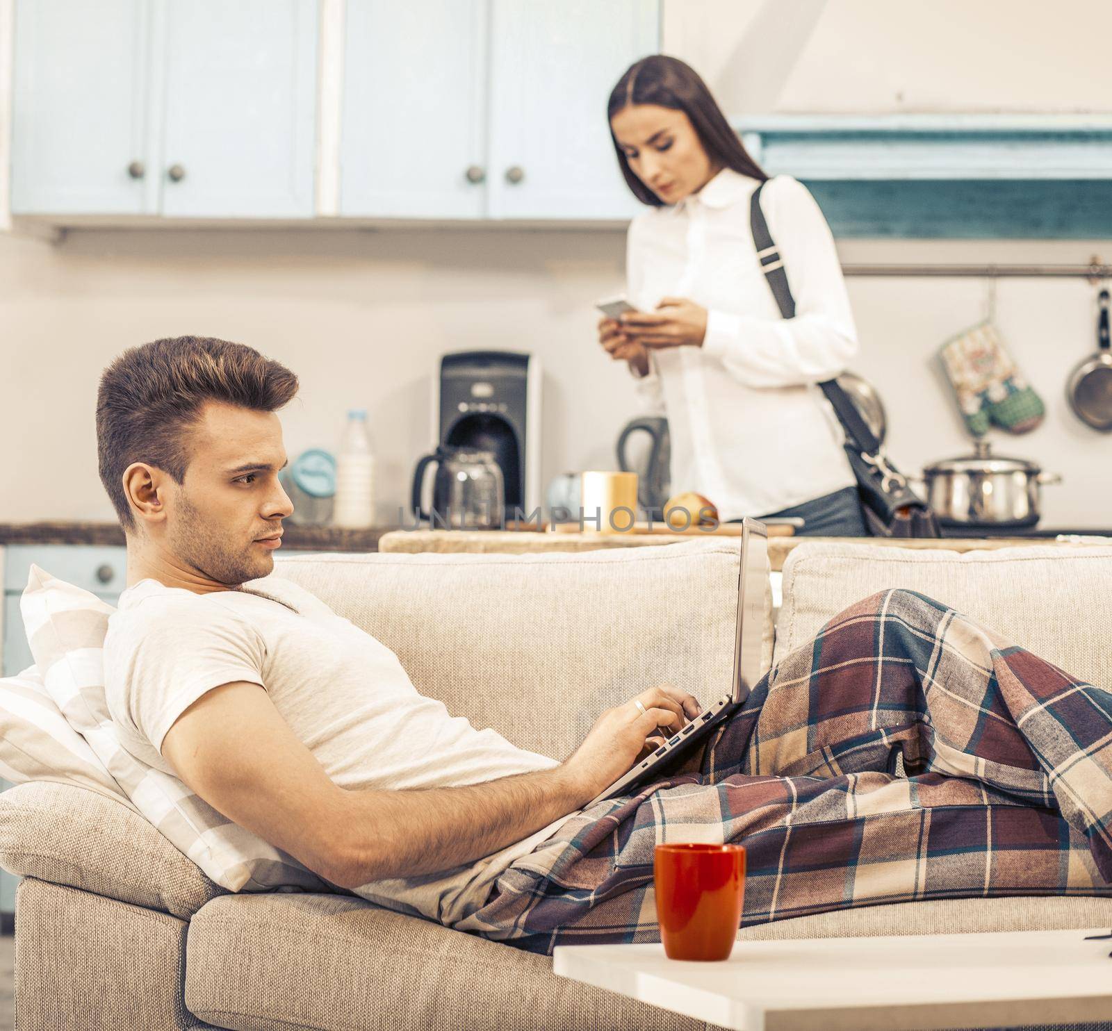 Man works with laptop stayingAt Home And lying on Sofa by LipikStockMedia