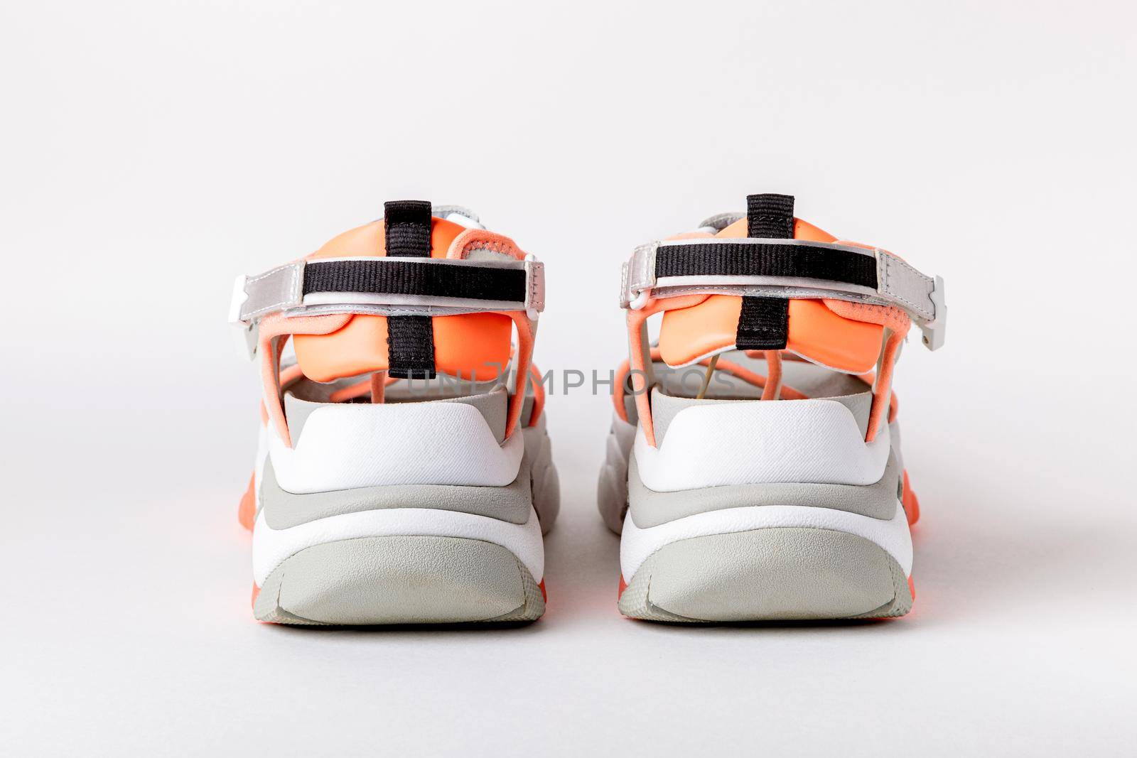 Women's, fashionable, sports sandals with orange accents on a white background. New youth shoes for girls.