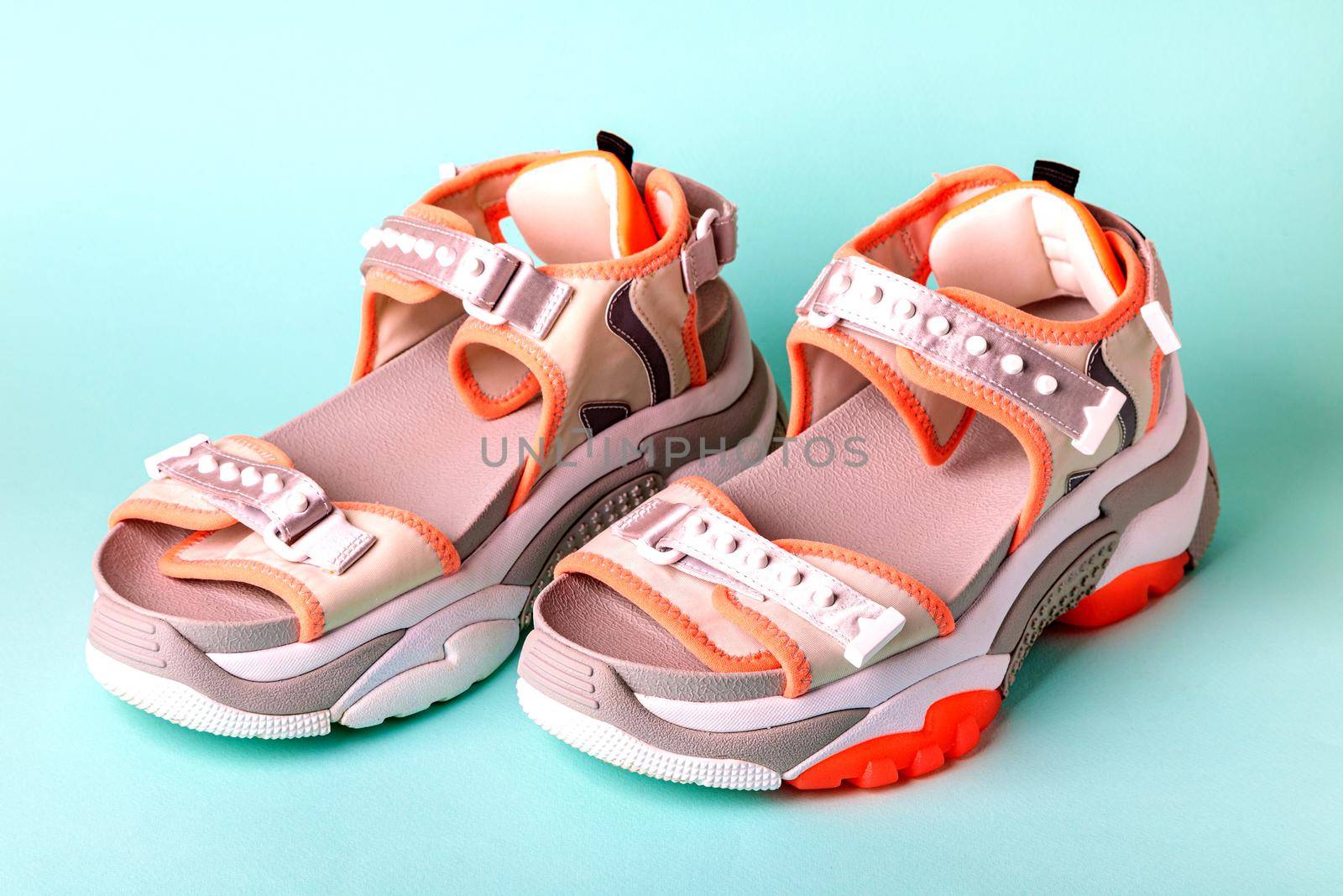 Women's, fashionable, sports sandals with orange accents on a blue background. New youth shoes for girls. Front view.