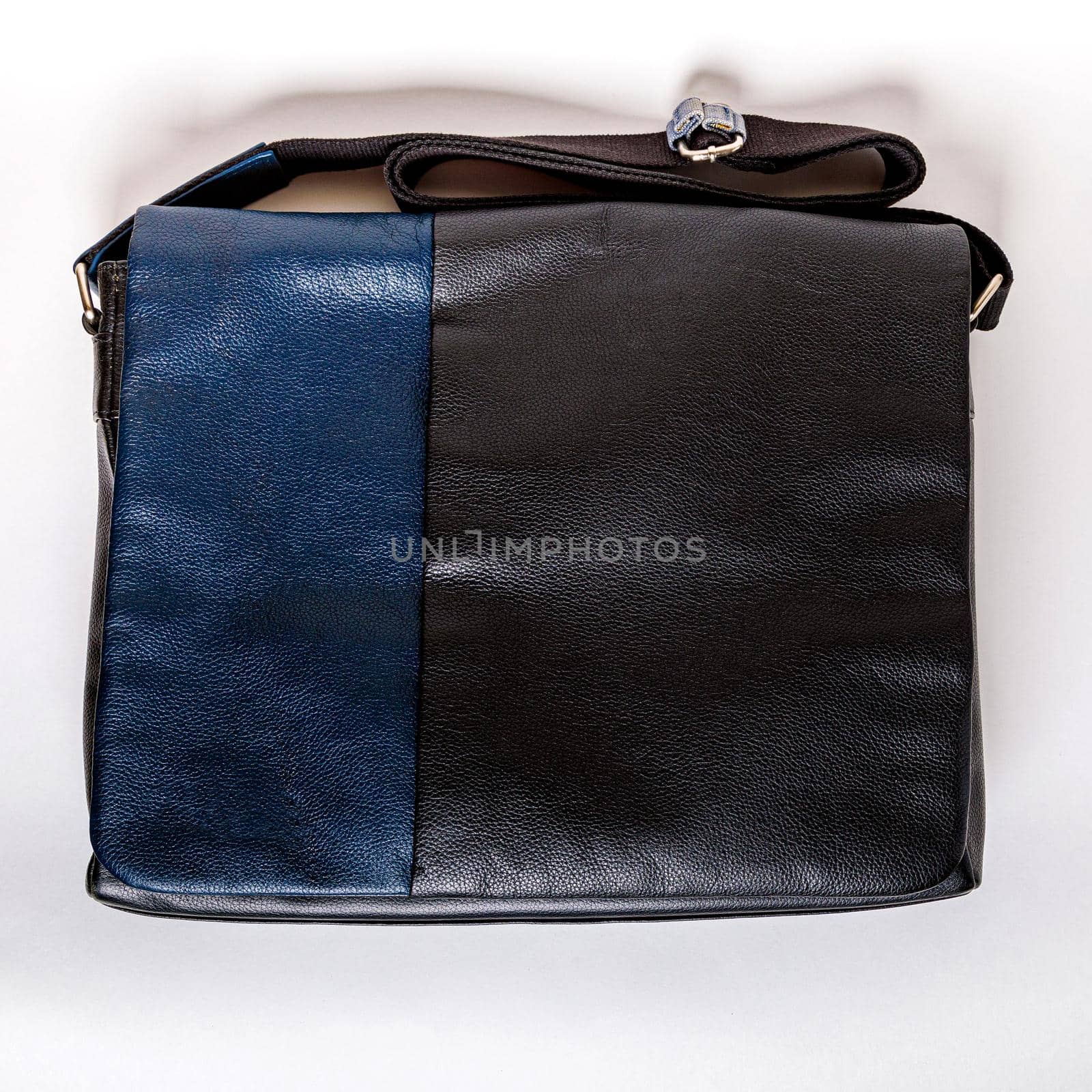 Men's leather bag in black and blue with a shoulder strap. Leather bag for a businessman. Close-up, top view.