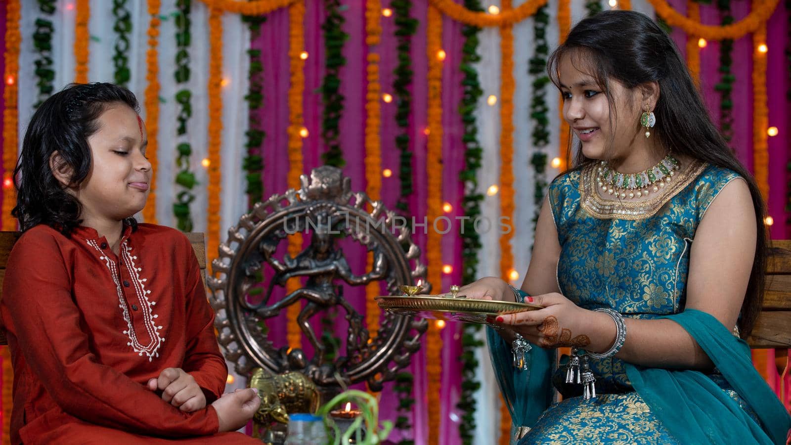 Indian families celebrating Raksha Bandhan festival a festival to celebrate the bond between brother and sister. Rakhi celebration in India. Feeding sweets, applying tikka.