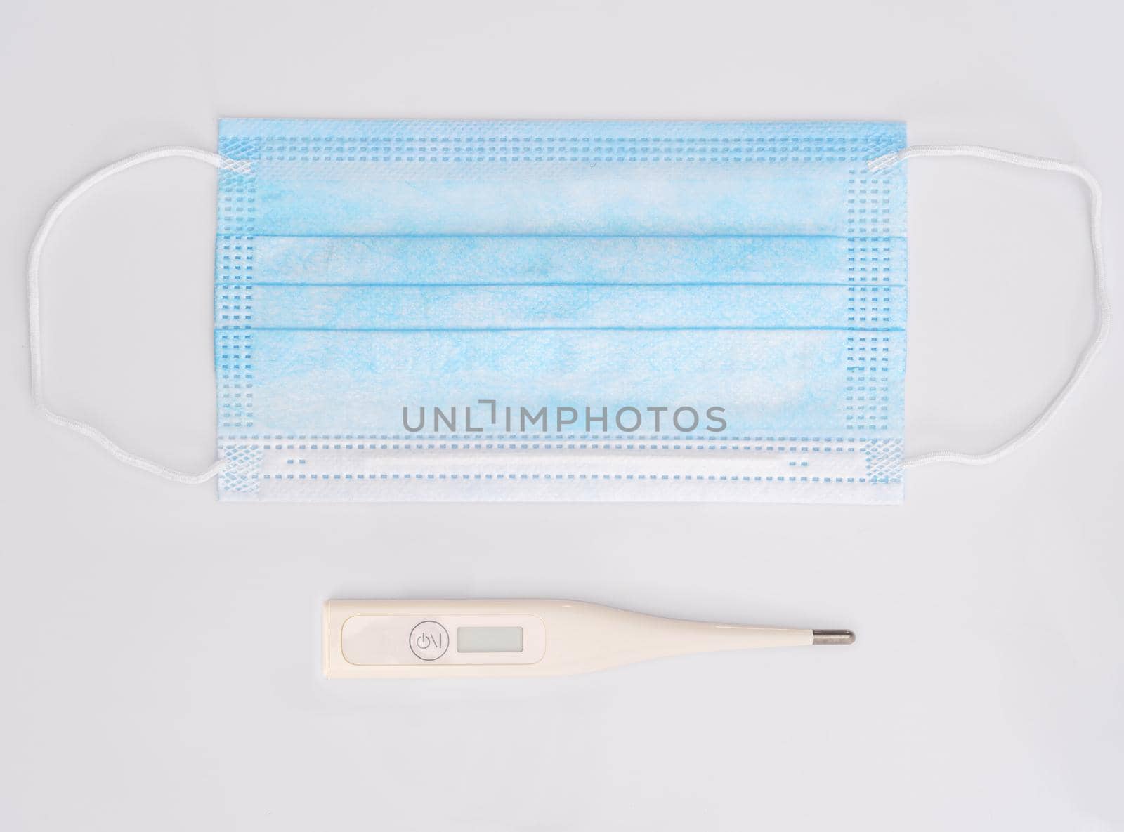 Medical respiratory surgical face mask filter with digital clinical thermometer ,Close-up of surgical medical mask on white background