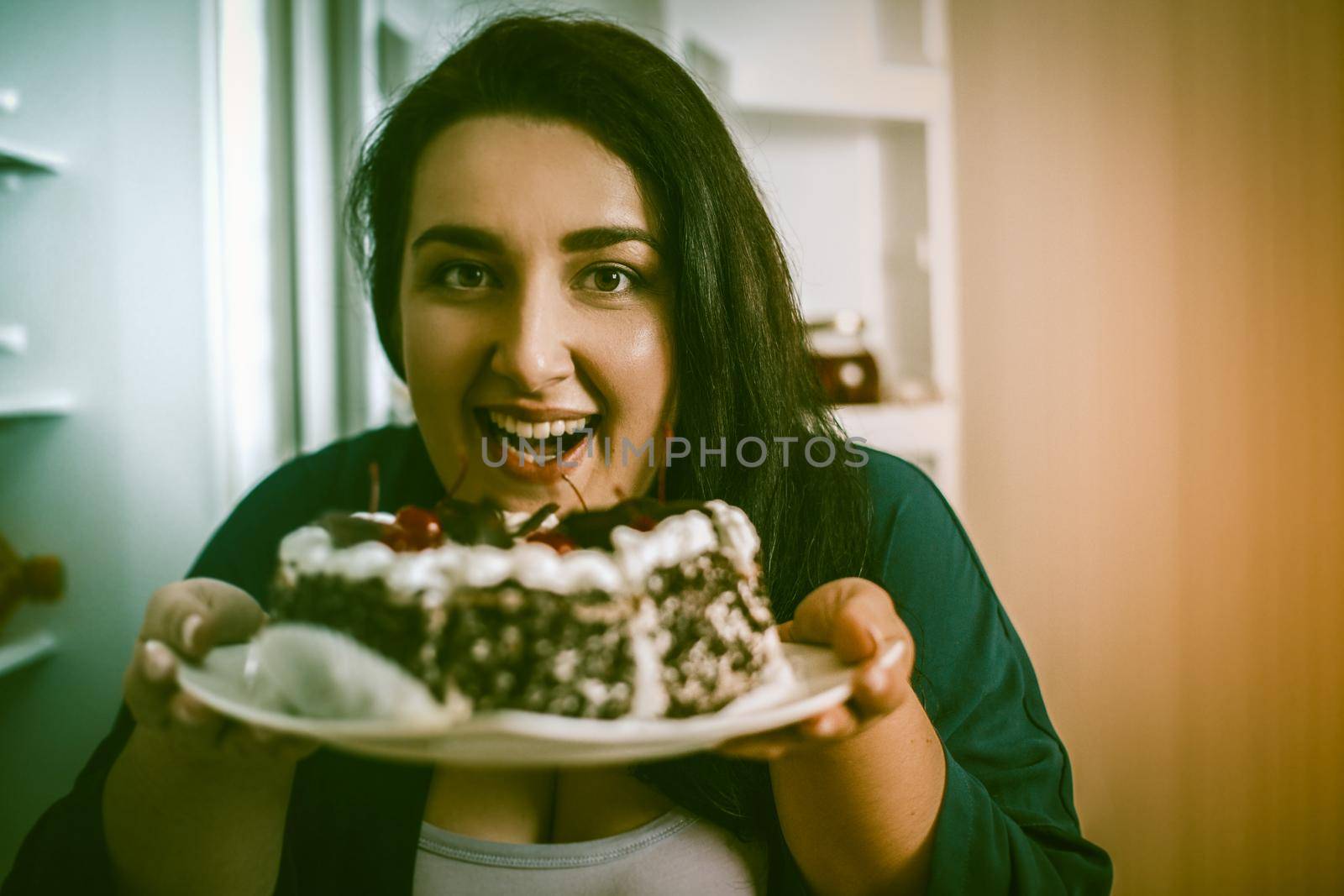 Plus Size Model Smiles Holding Plate With Chocolate Cake by LipikStockMedia