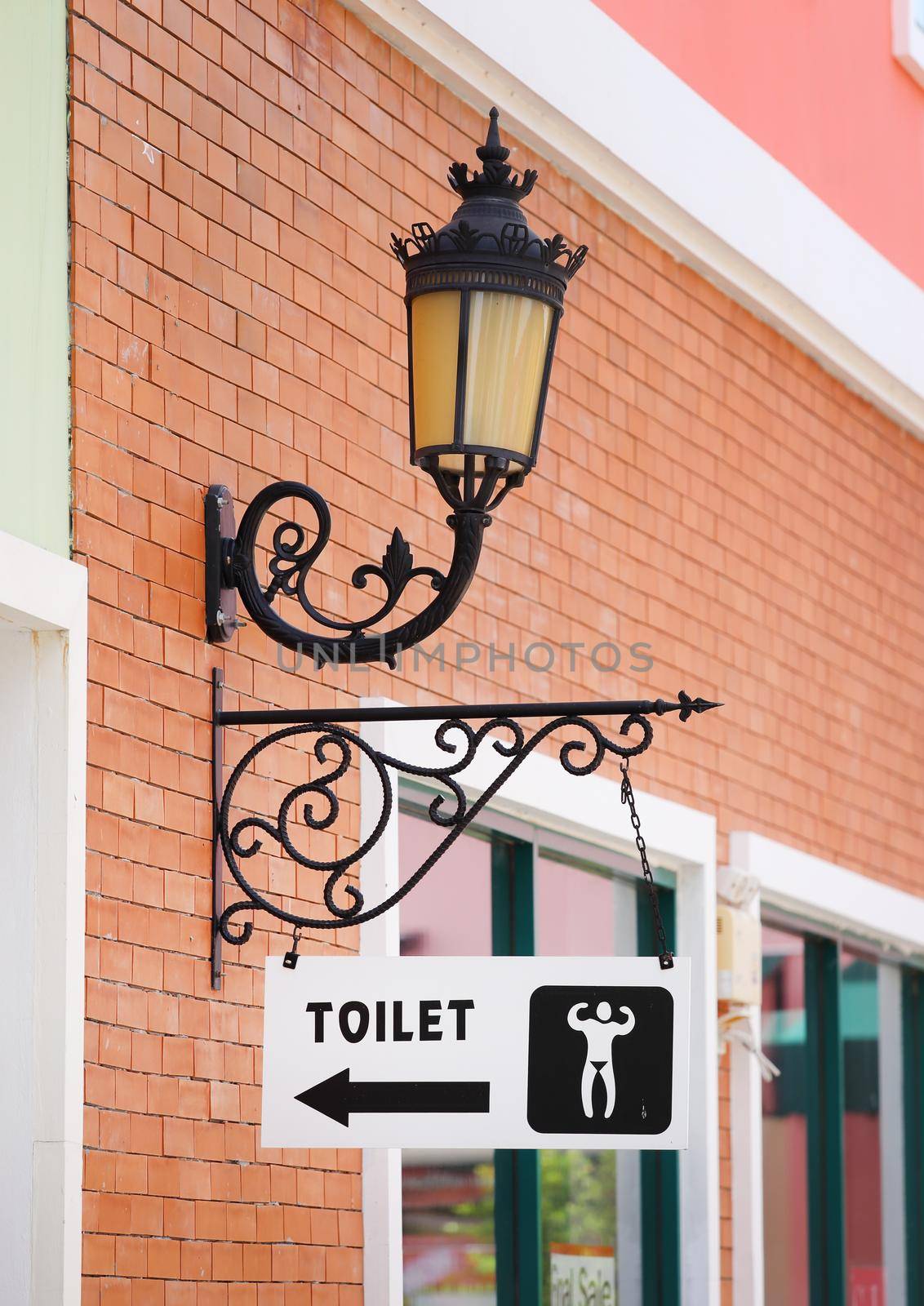 toilet sign hanging on brick wall and vintage lamp