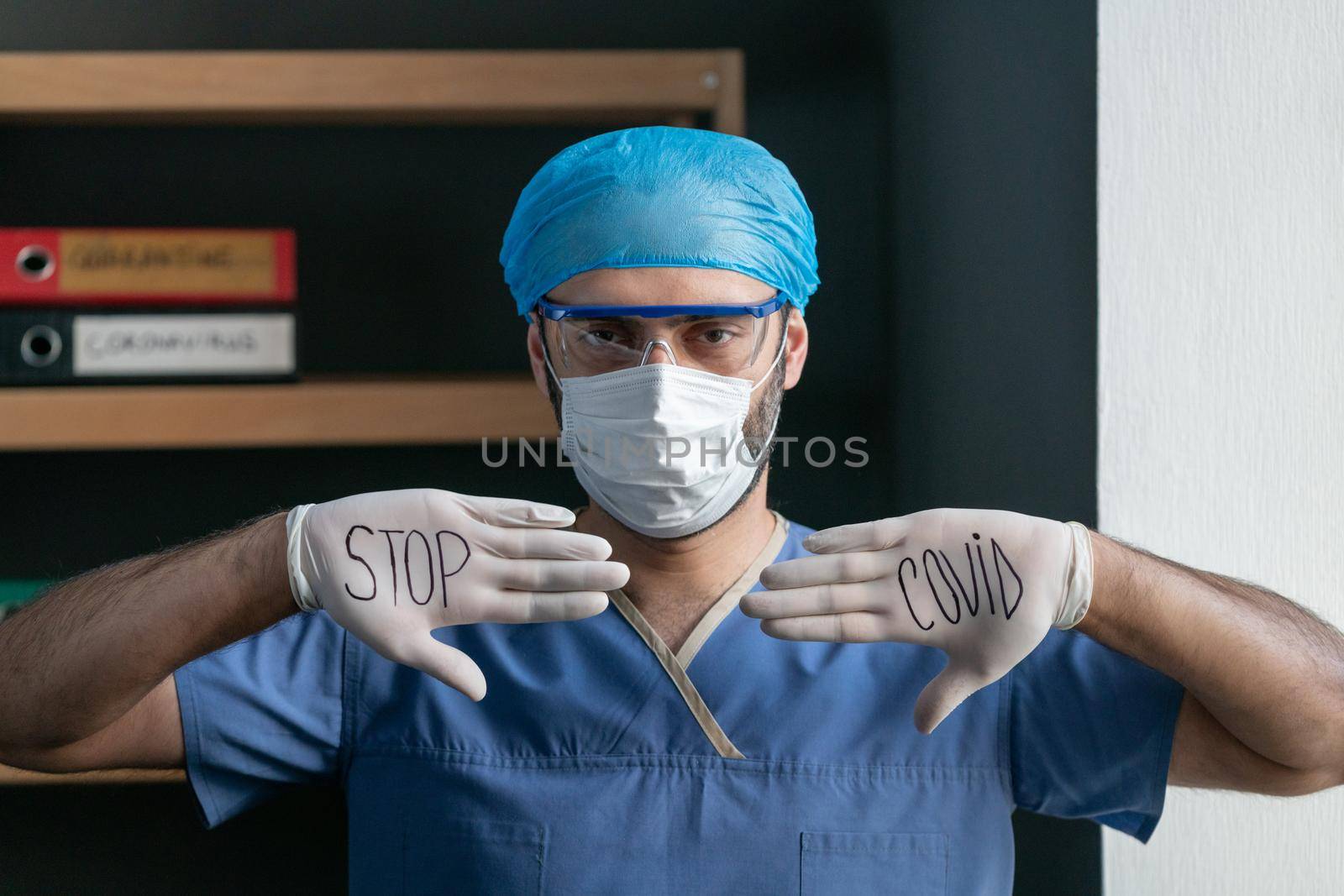 Male Doctor Shows Slogan To Stop Covid Virus Written With Black Marker On His White Gloves, Man In Blue Medical Uniform wants To Stop Covid-19 Or Coronavirus Epidemic, Quarantine Concept