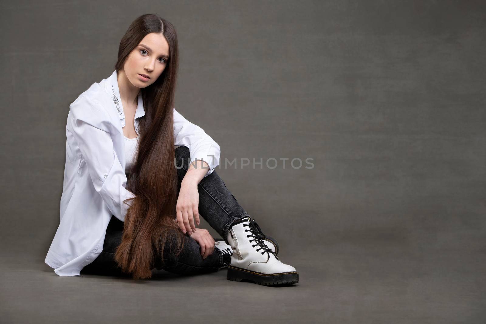 Beautiful brunette girl with very long hair on a gray background.