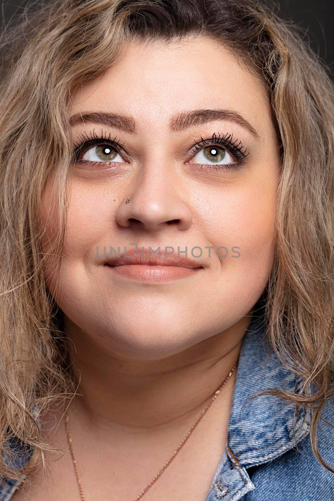 Portrait of a beautiful fat woman close-up on a gray background.