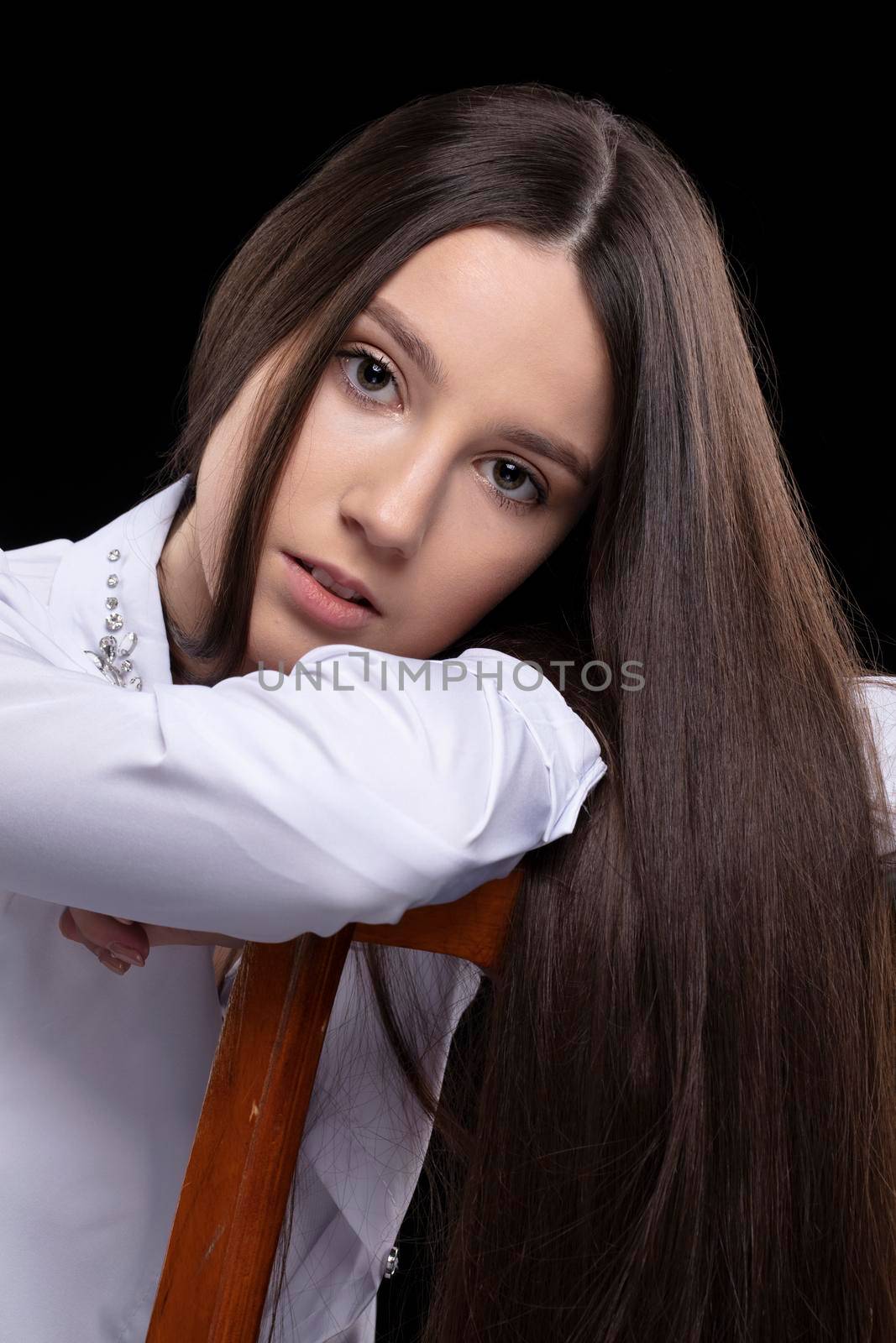 Beautiful brunette girl with long straight hair dressed in a white shirt.