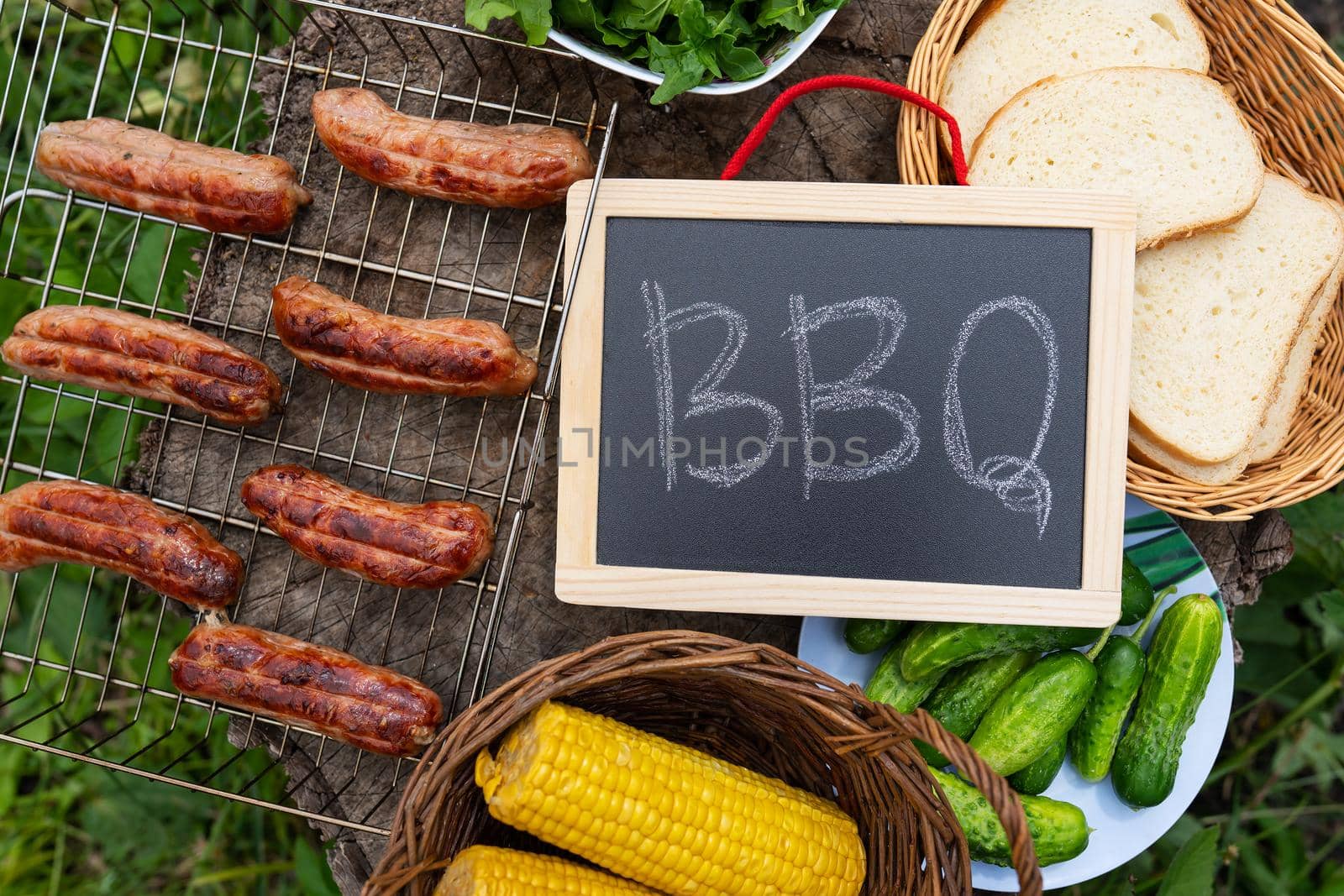 Barbecue inscription on chalkboard, grilled sausages, corn,bread. Outdoor recreation concept