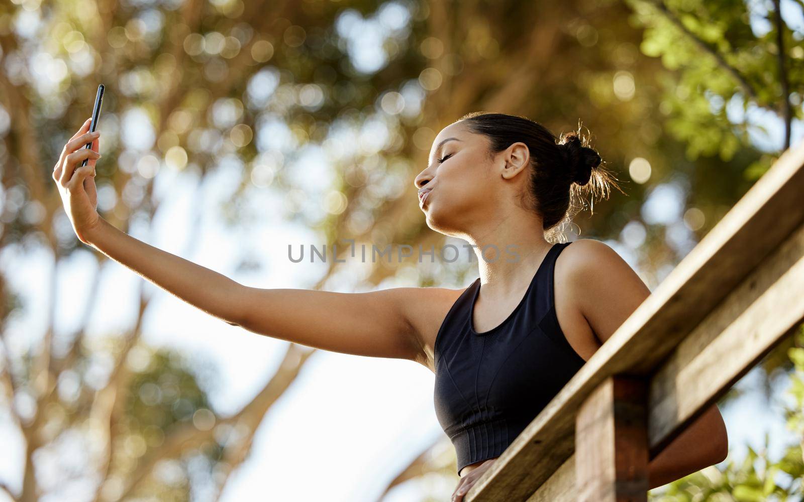 an attractive young female athlete taking selfies while exercising outdoors.