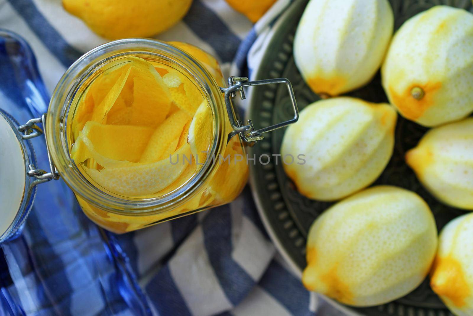 glass jar with lemon zest inside, next to fresh peeled lemons. Selective focus. Preparation of homemade limoncello liqueur, Italian traditional lemon liqueur.