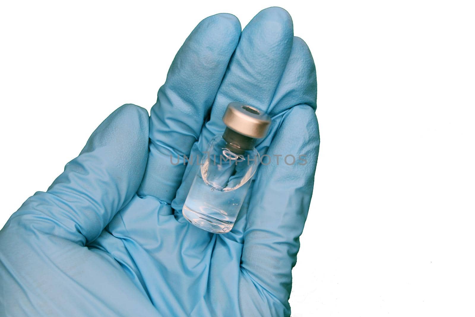 A hand in a blue medical glove close-up holding a vaccine against a light background. The concept of the fight against Covid19..