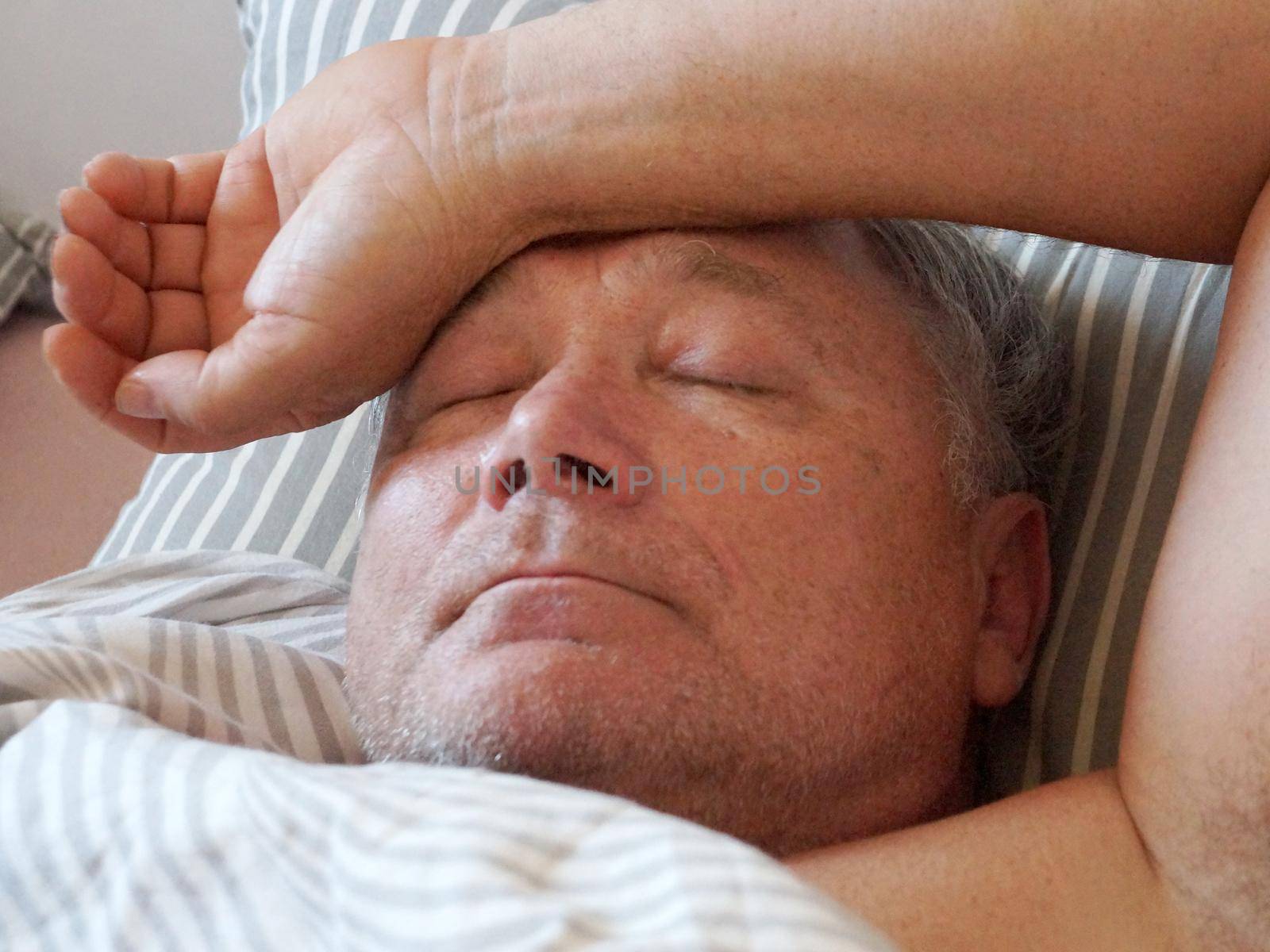 old man sleeping with his hand on his head close-up