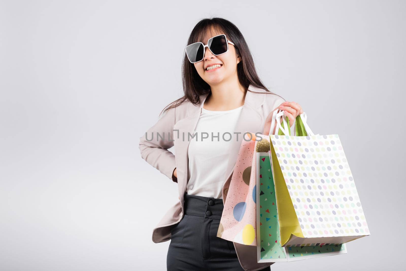 Happy woman with glasses confident shopper smiling holding online shopping bags colorful multicolor, Portrait excited Asian young female purchase studio shot isolated on white background, fashion sale