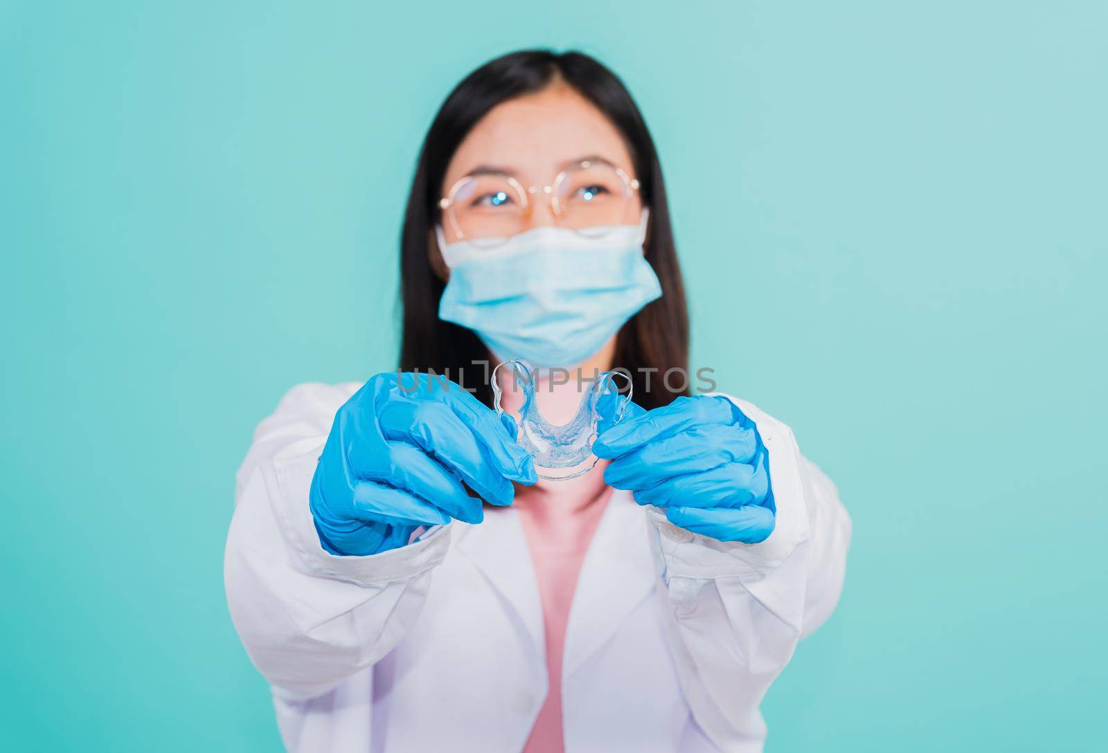 woman dentist holding silicone orthodontic retainers for teeth on hand by Sorapop