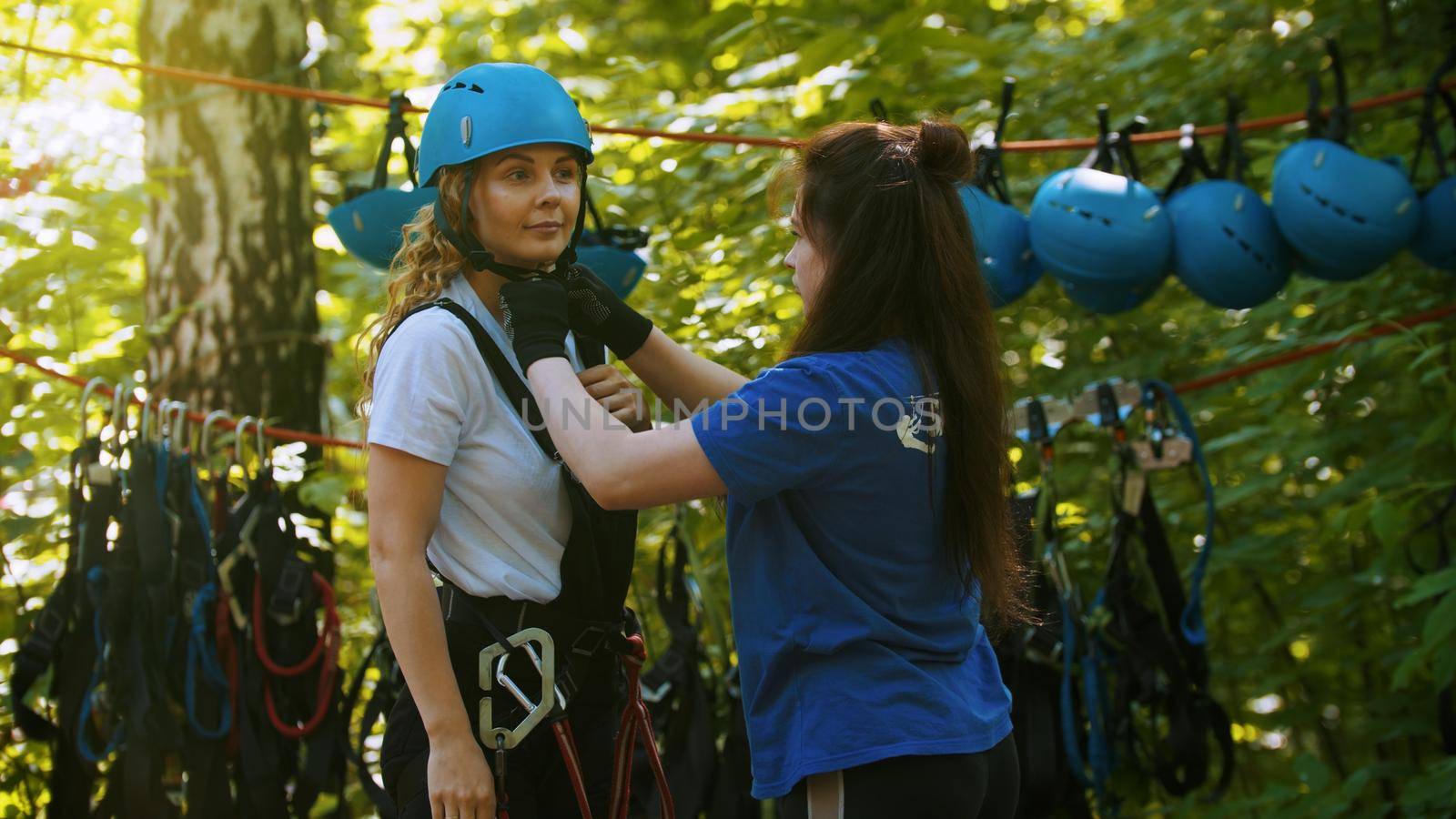 A young woman instructor putting a helmet on a head of the woman. Mid shot
