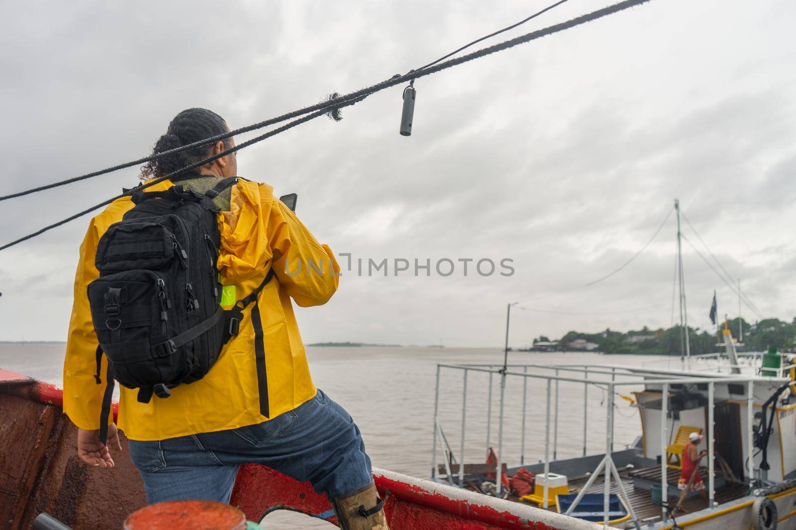 Latin fisherman with raincoat checking the weather forecast on his cell phone on top of his boat in Bluefields Nicaragua