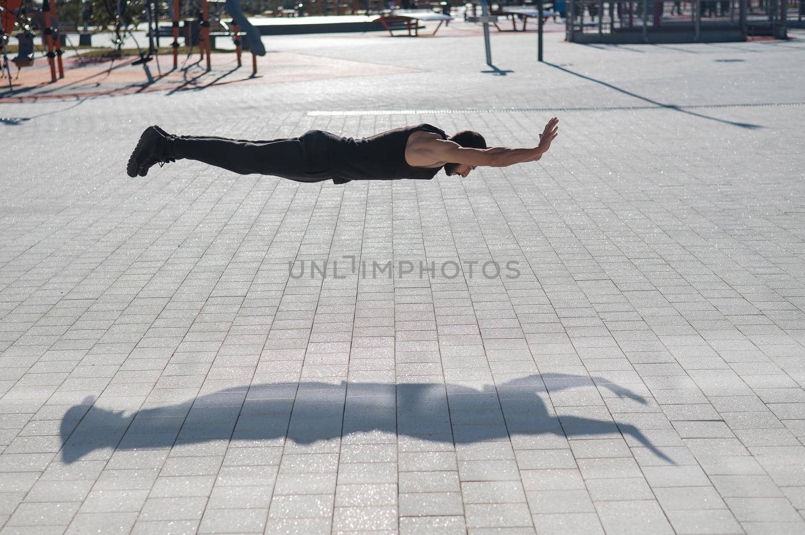 A man in black sportswear jumps doing push-ups in the park. by mrwed54