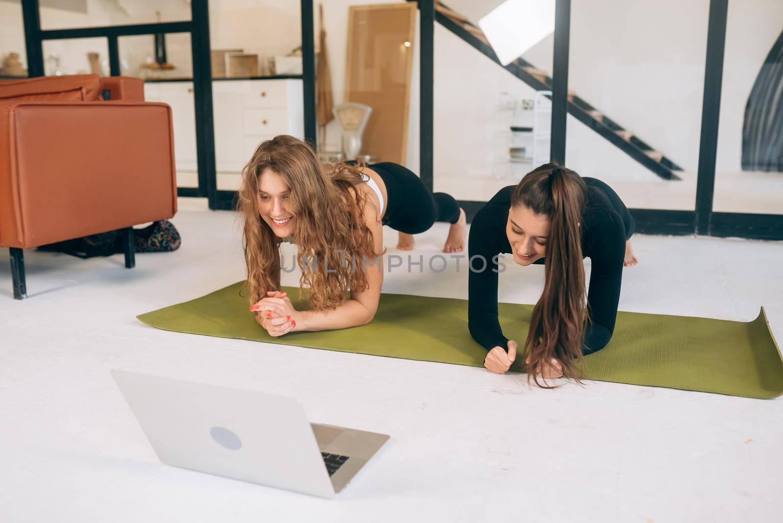 Two charming sports women, do yoga poses, exercises at home by teksomolika