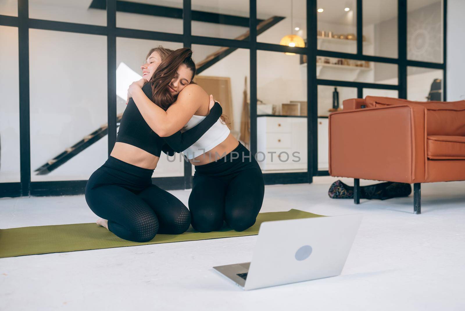 Two girlfriends hug each other after yoga by teksomolika