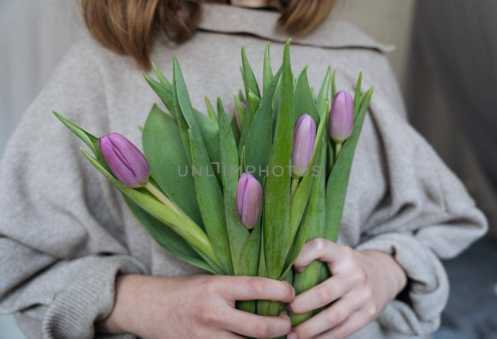 Close-up of a young woman holding a bunch of pink tulips by Varaksina