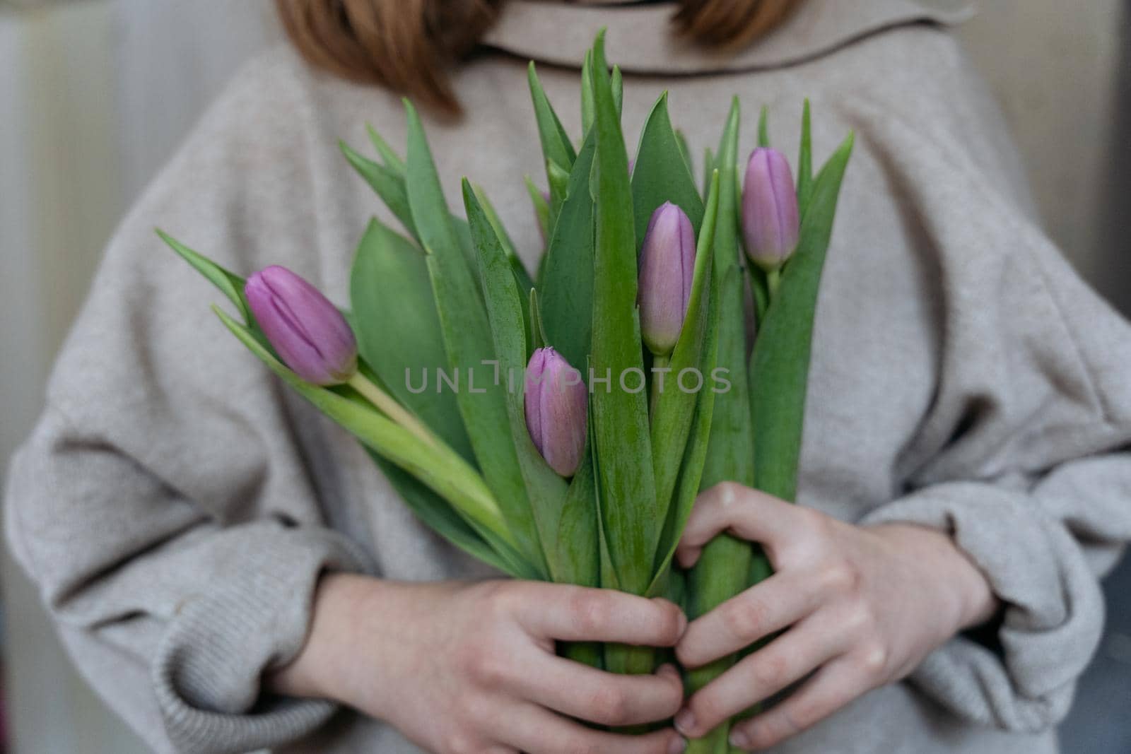 Close-up of a young woman holding a bunch of pink tulips by Varaksina
