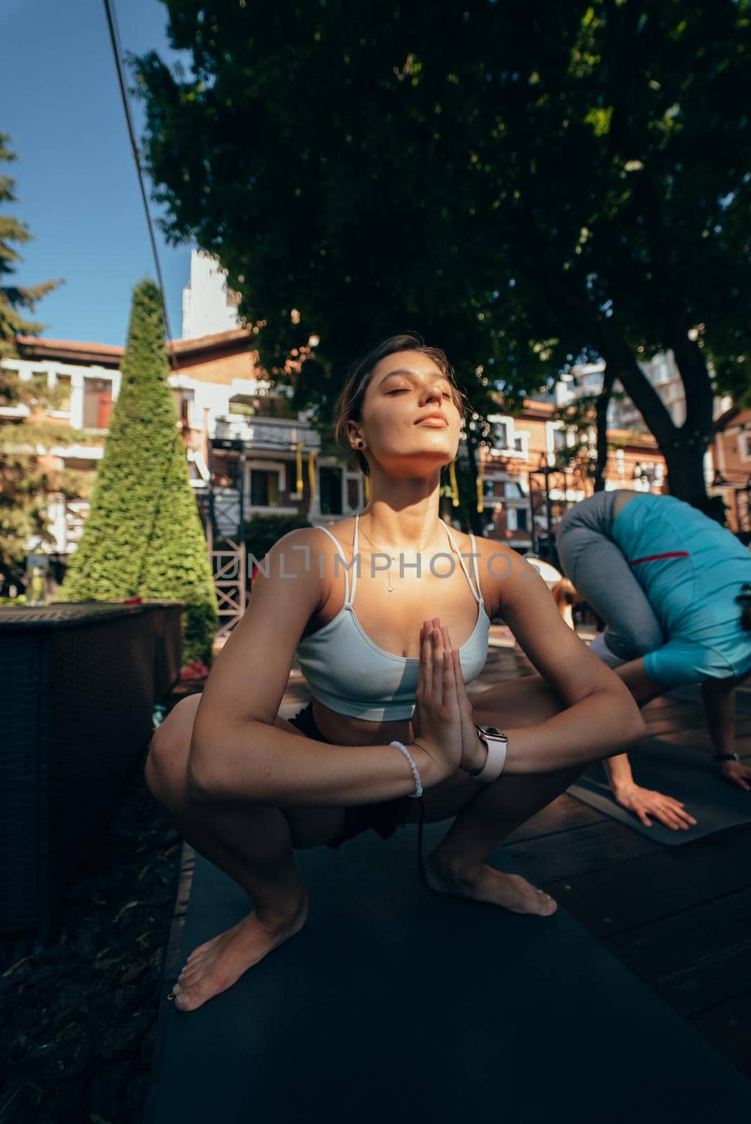 A woman does yoga together with her group in the open air by teksomolika