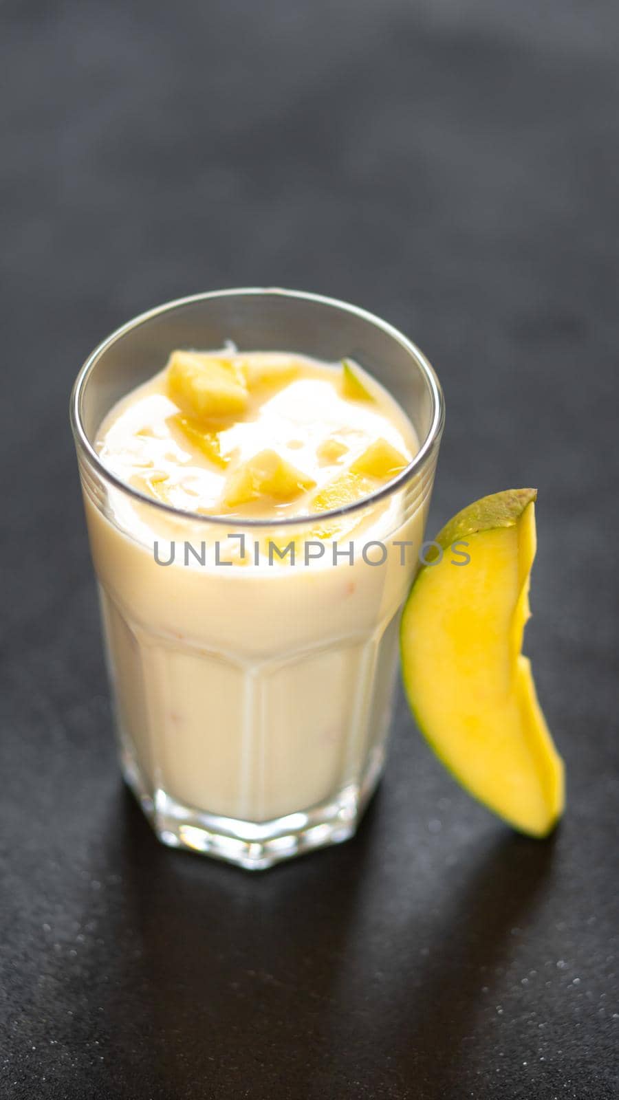 Milk shake on black background with mango pieces.