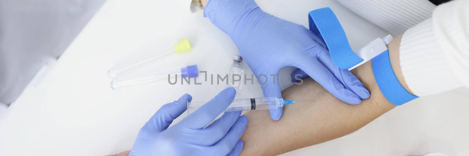 Top view of nurse injects liquid medication in womans vein with needle. Qualified medical worker take blood with syringe for test. Medicine, health concept