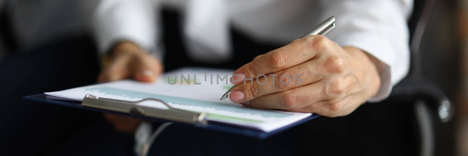 Female hand holding pen and put signature on business paper by kuprevich