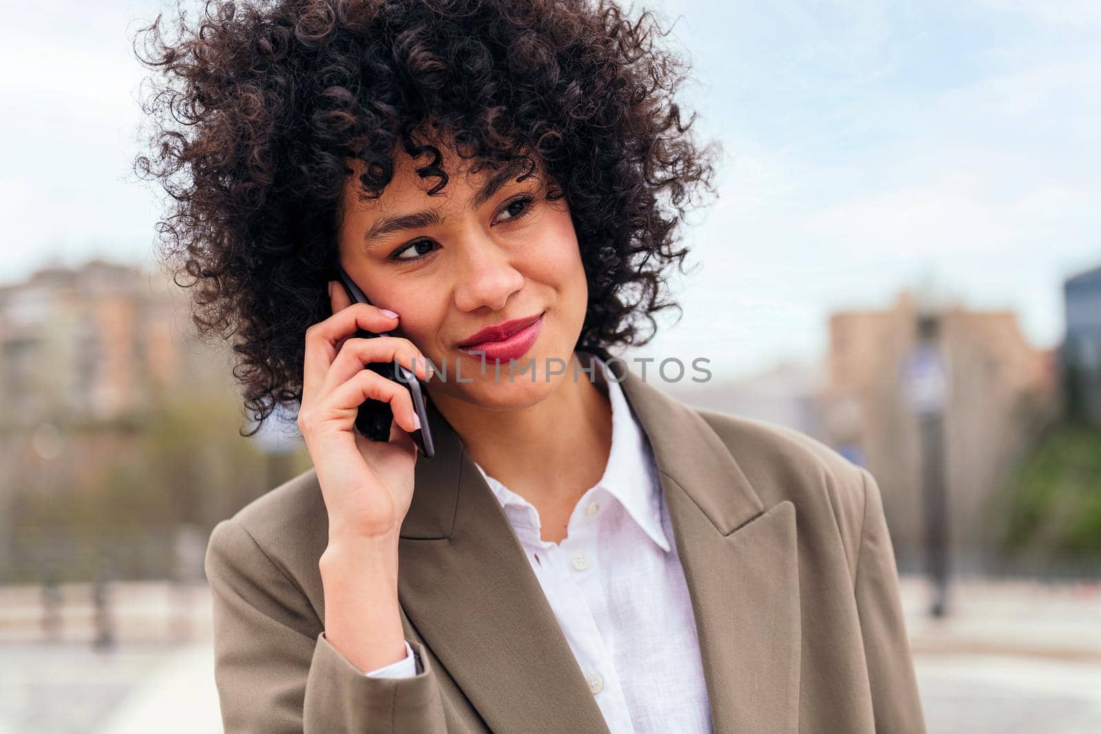 smiling latin woman talking by mobile phone, concept of communication and urban lifestyle, copy space for text