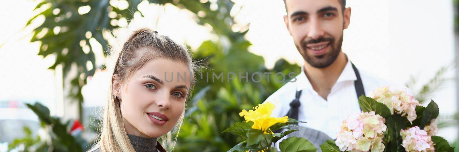 Portrait of cute florist workers hold flowers in pots, professional consultants ready to help with choice. Florist, nature, plant, studio, present concept