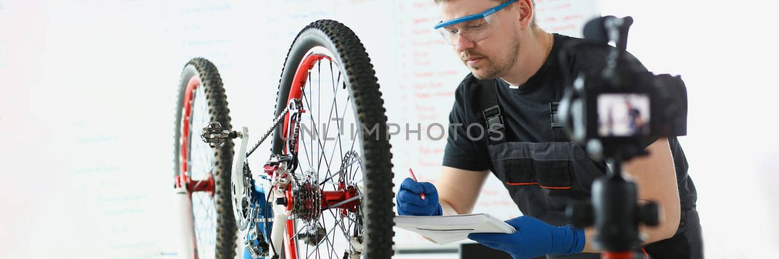 Portrait of concentrated middle aged mechanic writing down needed details to repair vehicle. Man record video for social media. Blogger, handyman concept