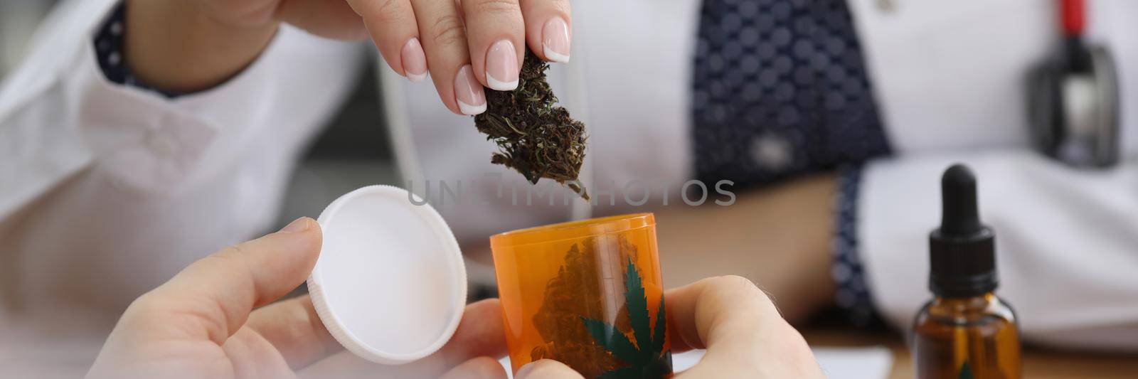Close-up of hospital worker put dried marijuana in plastic container. Doctor prescribe remedy for patient in office. Medicine, alternative medicine concept