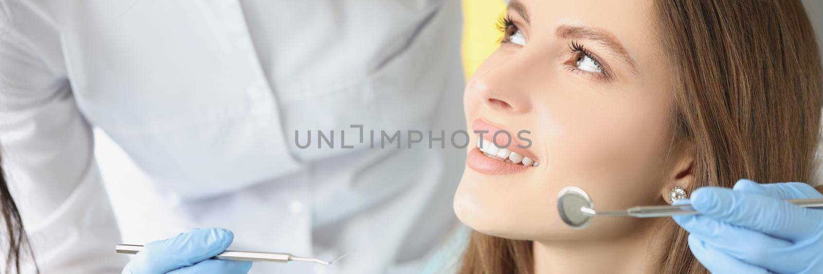 Portrait of female in dentist chair, appointment in dental clinic. Dentist woman ask to open mouth for examination. Medicine, dental, stomatology concept