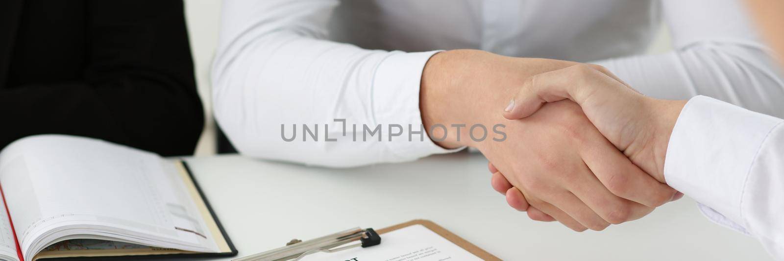 Close-up of partnership agreement between businesspeople, celebrate with handshake. Agreed on business conditions, sign contract paper. Agreement concept