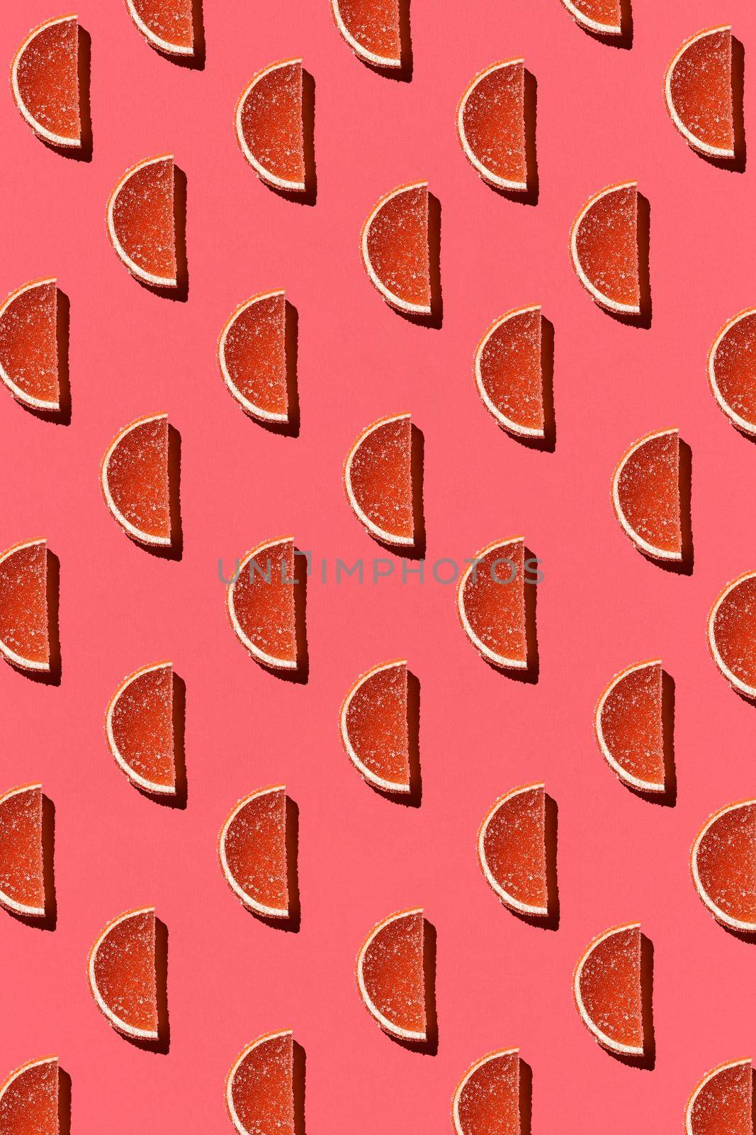 Pattern made of colorful candied fruits orange lemon on coral background. Flat lay. Minimal concept by nazarovsergey