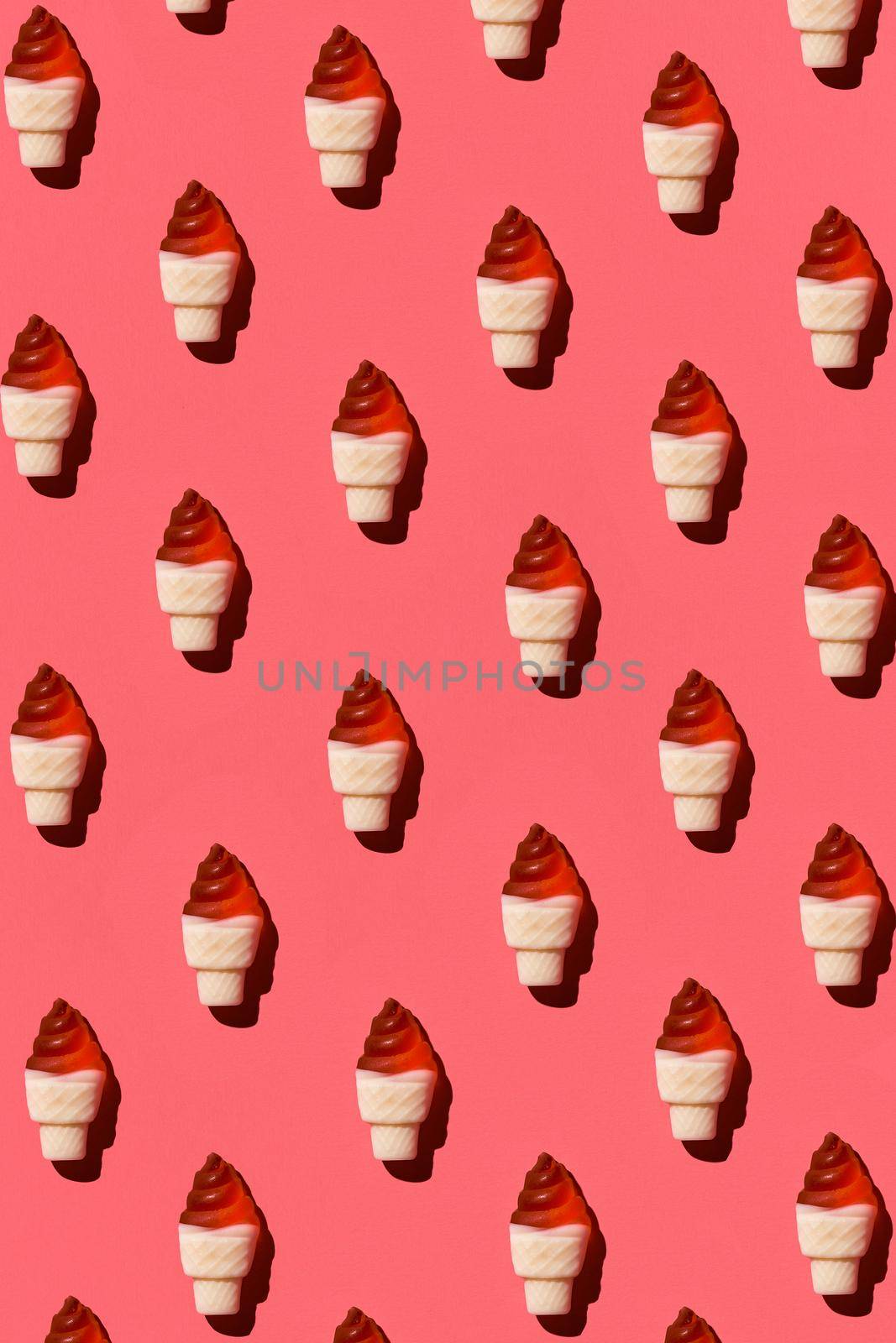 Pattern made of colorful jelly ice cream cones on coral background. Flat lay. Minimal concept by nazarovsergey