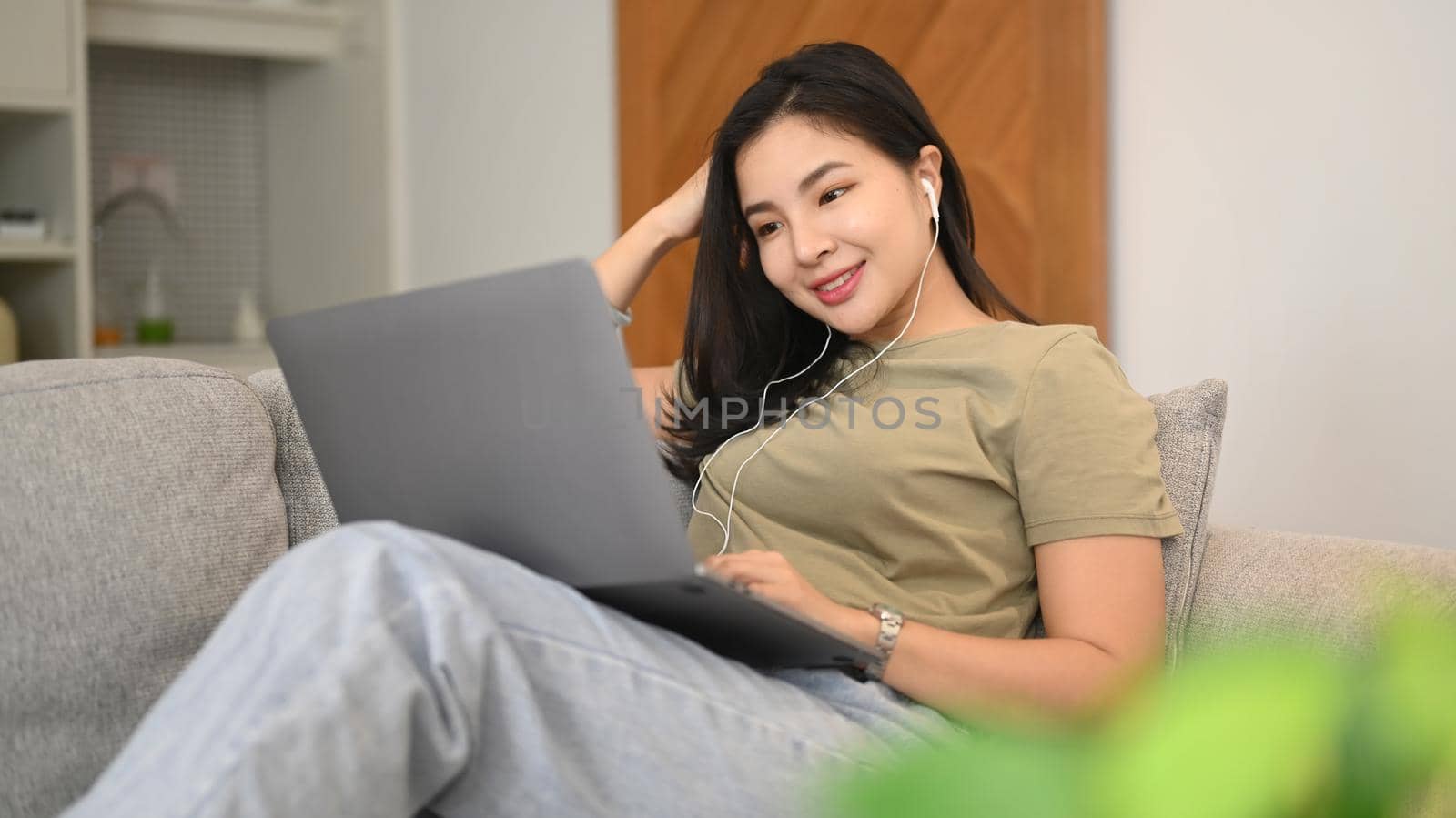 Smiling young asian woman ordering food online, chatting in social networks on laptop computer.