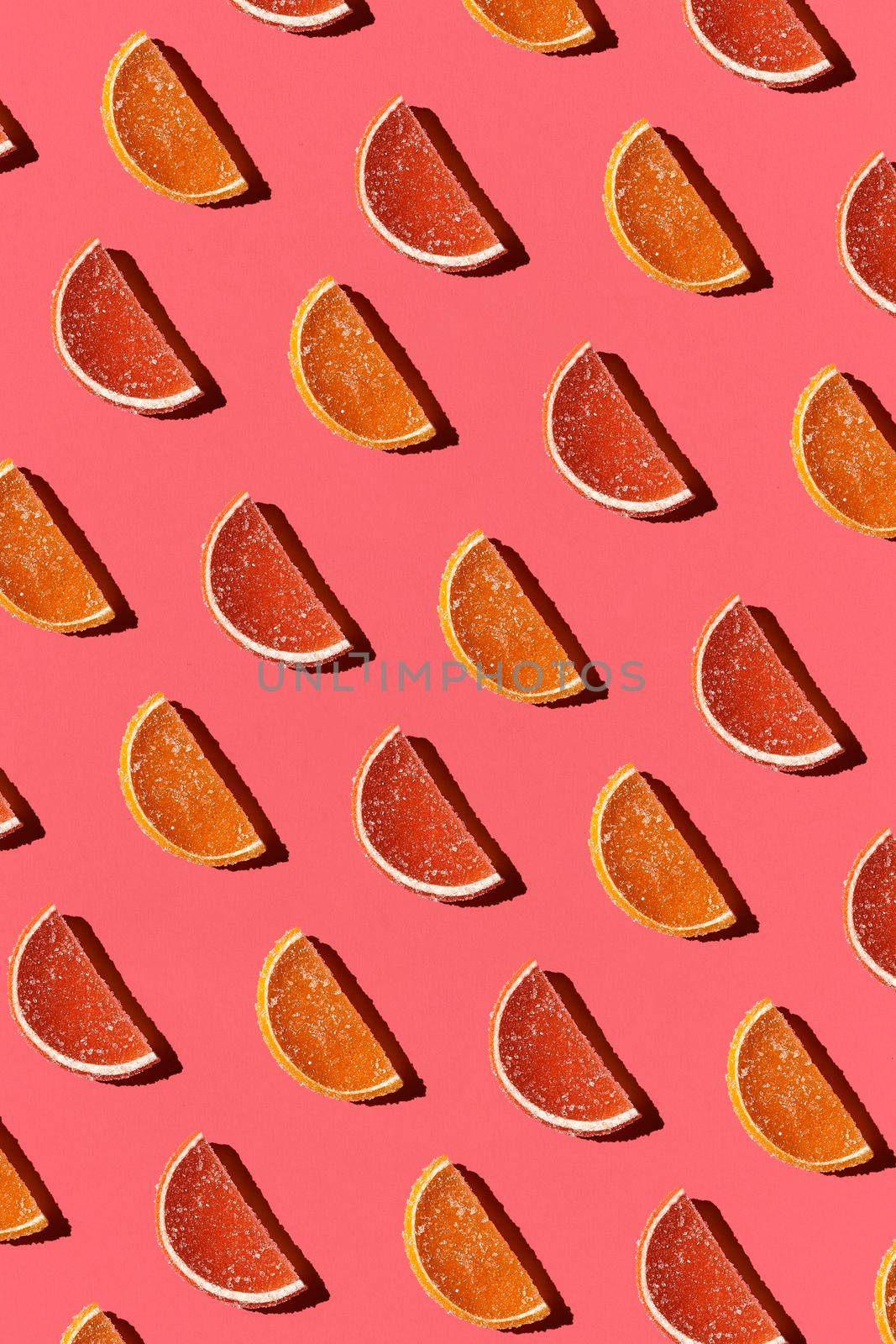 Photo of colorful candied fruits orange lemon on light pastel coral background. Top view. Mockup for positive idea. Strict chess order