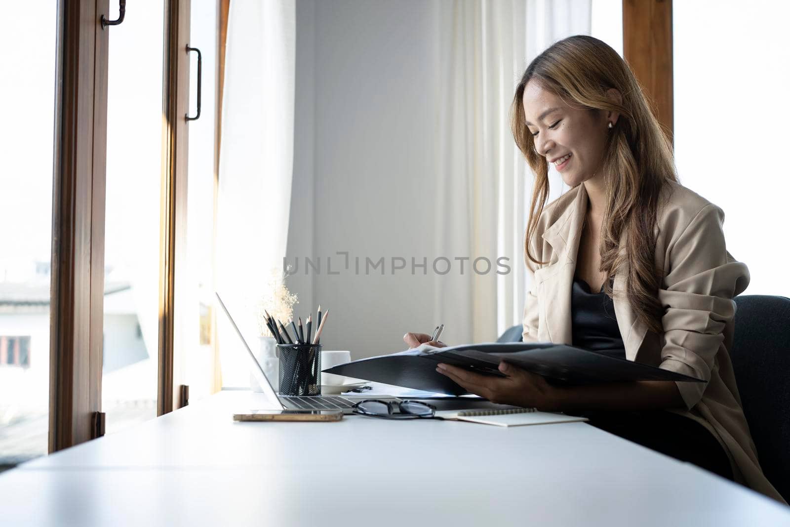 Happy businesswoman sitting in her workplace and working with computer laptop.
