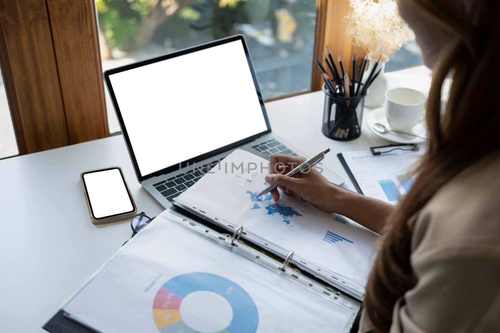 View over shoulder businesswoman checking financial graph and working with laptop.