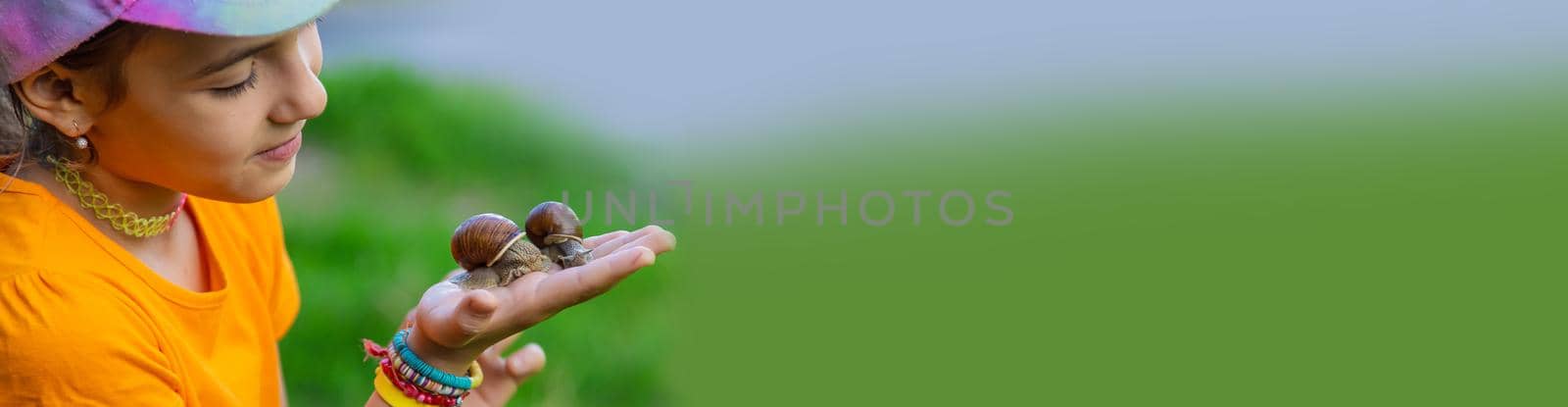 The child looks at the snail. Selective focus. by yanadjana