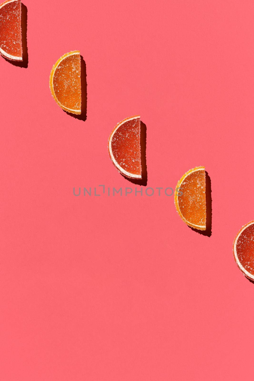 Pattern made of colorful candied fruits orange lemon on coral background. Flat lay. Minimal concept by nazarovsergey