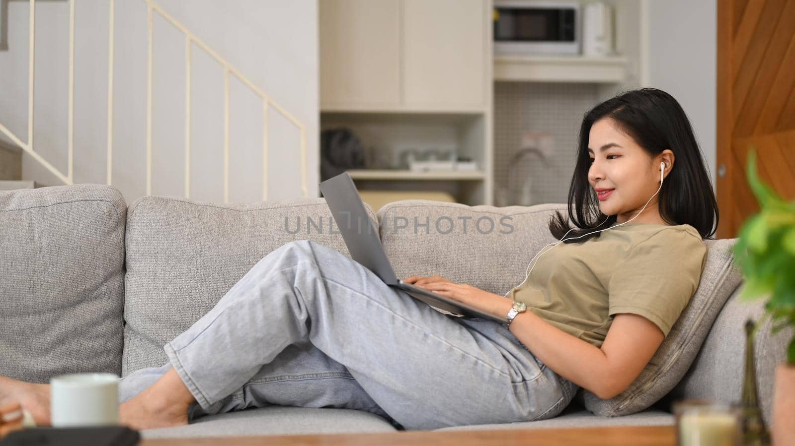Pleasant young asian woman surfing internet, chatting in social networks on laptop computer.