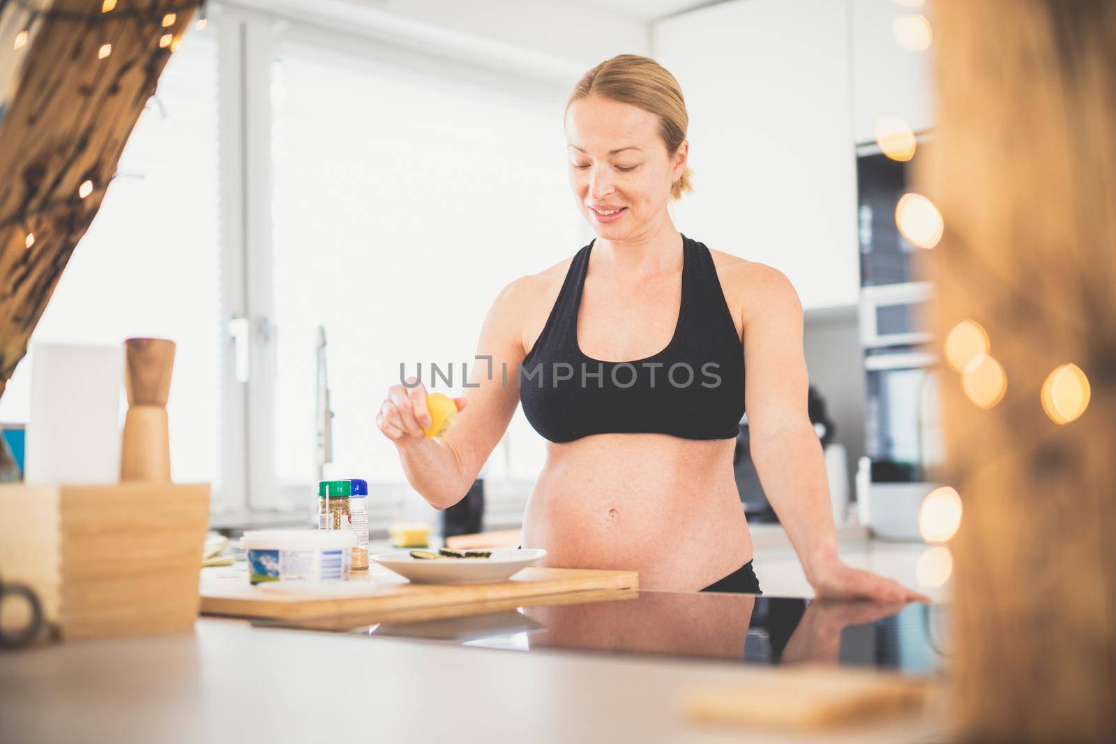Beautiful sporty fit young pregnant woman preparing healthy meal in home kitchen. Healty lifestyle concept